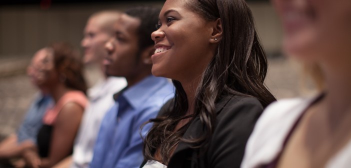 Stock photo of a diverse group of young people smiling in an audience