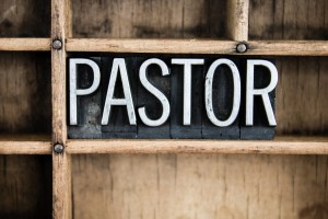 The word "PASTOR" written in vintage metal letterpress type in a wooden drawer with dividers.