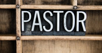 The word "PASTOR" written in vintage metal letterpress type in a wooden drawer with dividers.