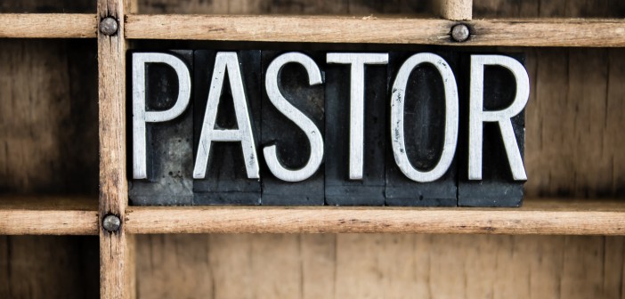 The word "PASTOR" written in vintage metal letterpress type in a wooden drawer with dividers.