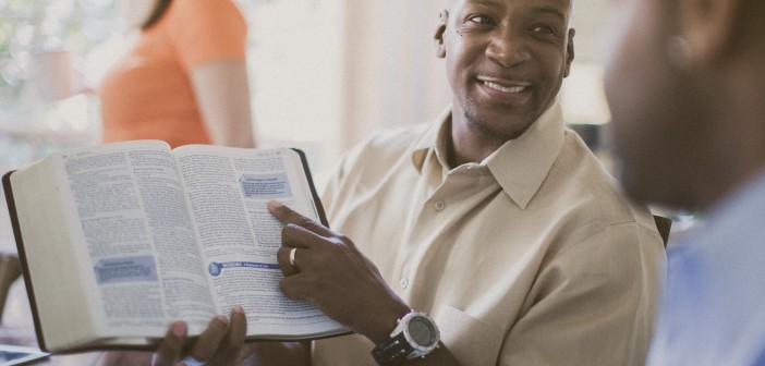Stock photo of an African American man pointing something out in an open bible