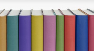 Stock photo of a bunch of standing books pressed against one another - as if on a bookshelf - with a rainbow of colored spines with no titles