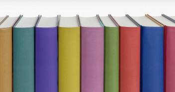 Stock photo of a bunch of standing books pressed against one another - as if on a bookshelf - with a rainbow of colored spines with no titles