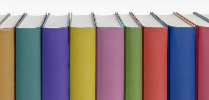 Stock photo of a bunch of standing books pressed against one another - as if on a bookshelf - with a rainbow of colored spines with no titles