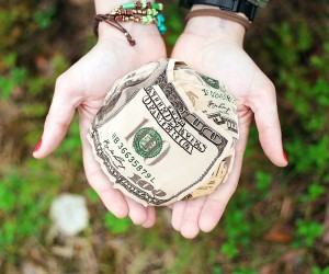 Stock photo of a pair of hands holding a ball of $100 bills