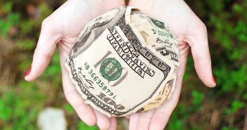 Stock photo of a pair of hands holding a ball of $100 bills