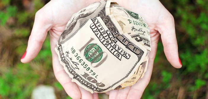 Stock photo of a pair of hands holding a ball of $100 bills