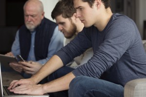 Stock photo of a mixed-age group of white men working on various electronic devices