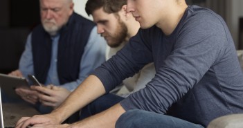 Stock photo of a mixed-age group of white men working on various electronic devices