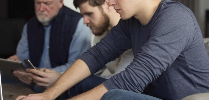 Stock photo of a mixed-age group of white men working on various electronic devices