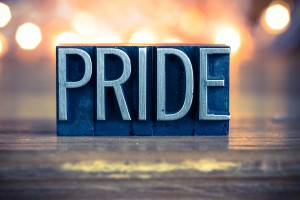 Stock photo of the word "PRIDE" carved out of wood and painted silver