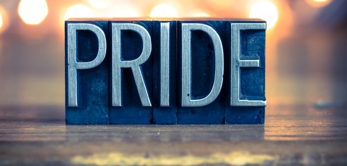 Stock photo of the word "PRIDE" carved out of wood and painted silver