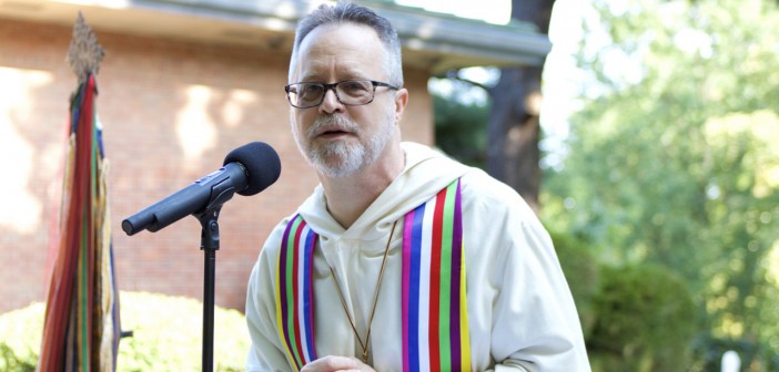 Photo of an older white clergyman preaching outside at Wesley Theological Seminary