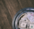 Money-filled offering plate on a wooden table