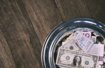 Money-filled offering plate on a wooden table