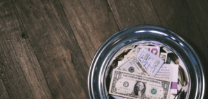 Money-filled offering plate on a wooden table