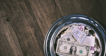 Money-filled offering plate on a wooden table