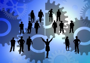 Clip art of a group of silhouettes of people in amidst a sea of gears