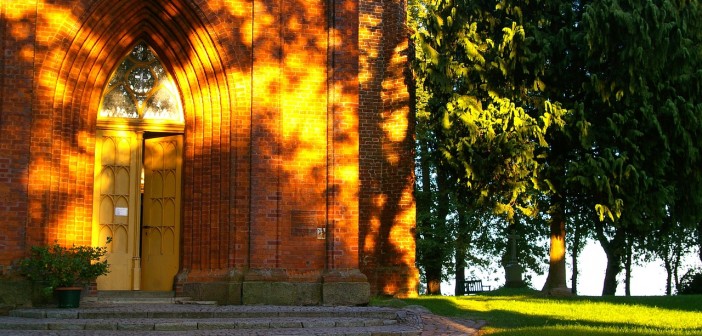 Stock photo of the exterior of a big brick church/chapel in a park.