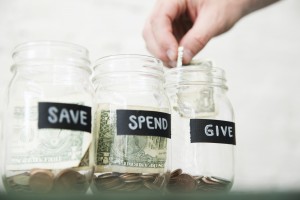 Photo of person adding money to a jar labeled "give"