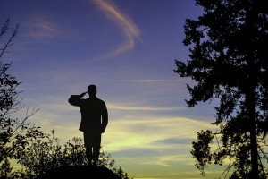 Stock photo of a heavily back-lit soldier saluting outdoors