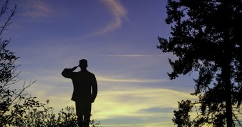 Stock photo of a heavily back-lit soldier saluting outdoors