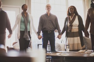 Group of people standing and holding hands in prayer