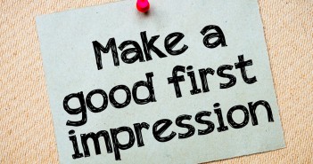Stock photo of a notecard with "Make a good first impression" printed on it and tacked to a bulletin board