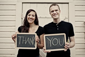 Stock photo of a young white man and woman holding up two chalkboards that read "THANK YOU"