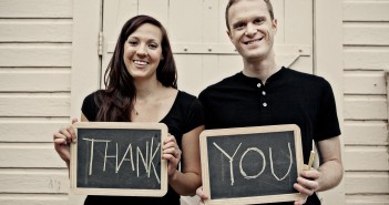 Stock photo of a young white man and woman holding up two chalkboards that read "THANK YOU"