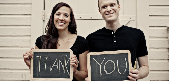 Stock photo of a young white man and woman holding up two chalkboards that read "THANK YOU"