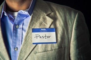 Stock photo of someone wearing a blazer and button down shirt with a nametag that reads "Hello my name is PASTOR"