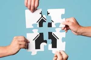 Stock photo of four individuals putting a puzzle together that depicts a church