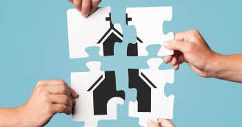 Stock photo of four individuals putting a puzzle together that depicts a church