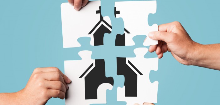 Stock photo of four individuals putting a puzzle together that depicts a church