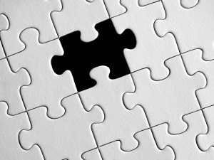 Stock photo of an all-white puzzle that is completely finished except for one middle piece that's missing