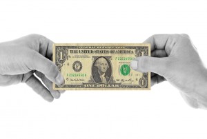 Stock photo of a black and white pair of hands holding a $1 bill