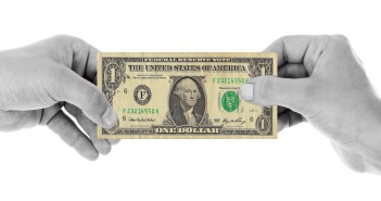 Stock photo of a black and white pair of hands holding a $1 bill