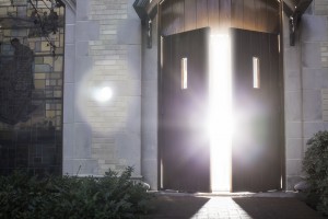 Stock photo of a set of wooden doors that are slightly open and allowing light to flood through them