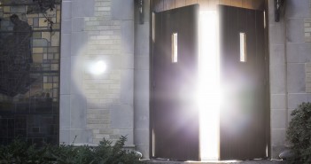 Stock photo of a set of wooden doors that are slightly open and allowing light to flood through them