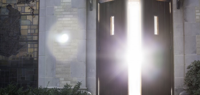 Stock photo of a set of wooden doors that are slightly open and allowing light to flood through them