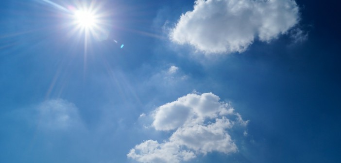 Stock photo of a clear, sunny sky with two fluffy clouds