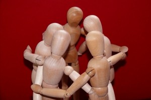 Stock photo of a group of wooden manikins posed to be in a huddle
