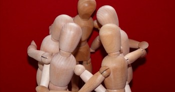 Stock photo of a group of wooden manikins posed to be in a huddle