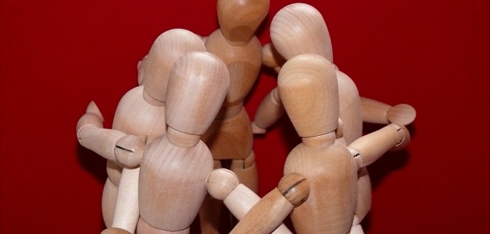 Stock photo of a group of wooden manikins posed to be in a huddle