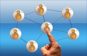 Stock photo of a hand pointing to a clip art of an androgynous individual who is part of a social network