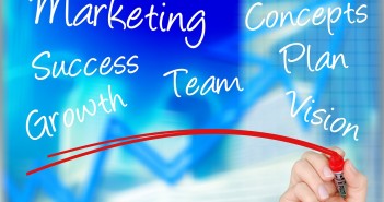 Stock photo of a hand writing "MARKETING" "CONCEPTS" "SUCCESS" "TEAM" "PLAN" "GROWTH" and "VISION" on a whiteboard