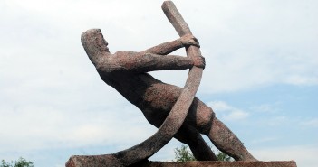 Stock photo of a statue of a man bending a metal pipe