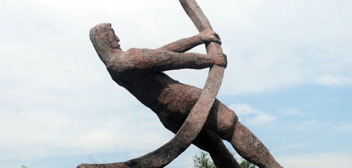 Stock photo of a statue of a man bending a metal pipe