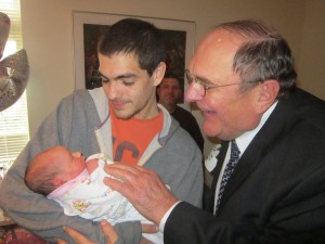 Stock photo a young man holding a baby with an older man looking on
